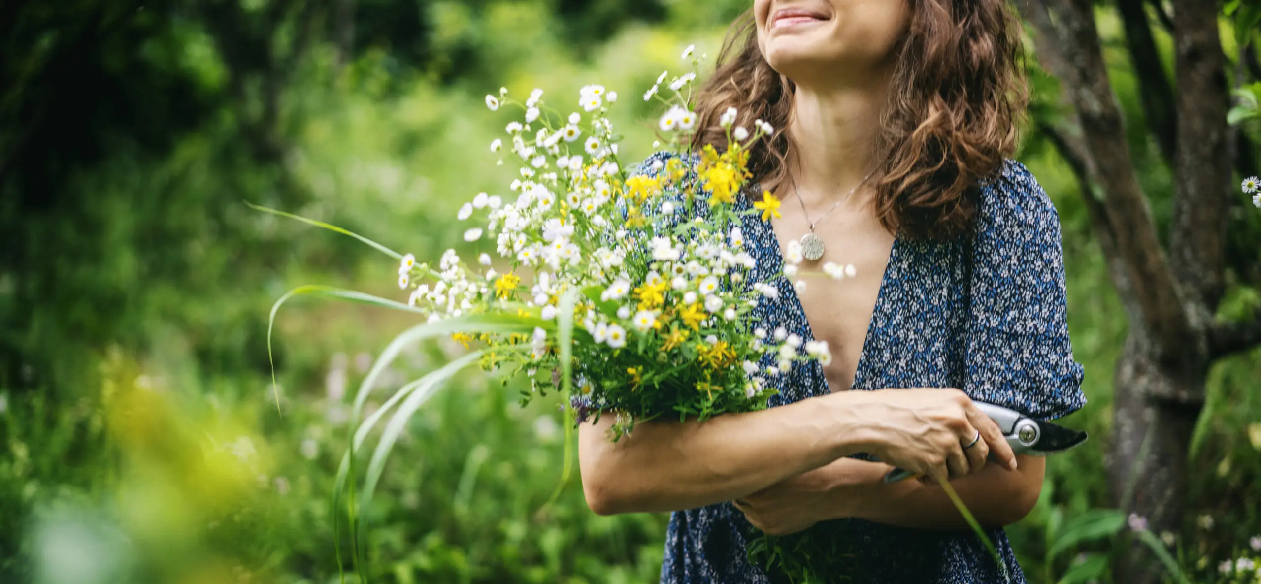 Young Cheerful Smiling Woman In Summer Dress Holding A Bouquet Of Wildflowers In A Summer Garden